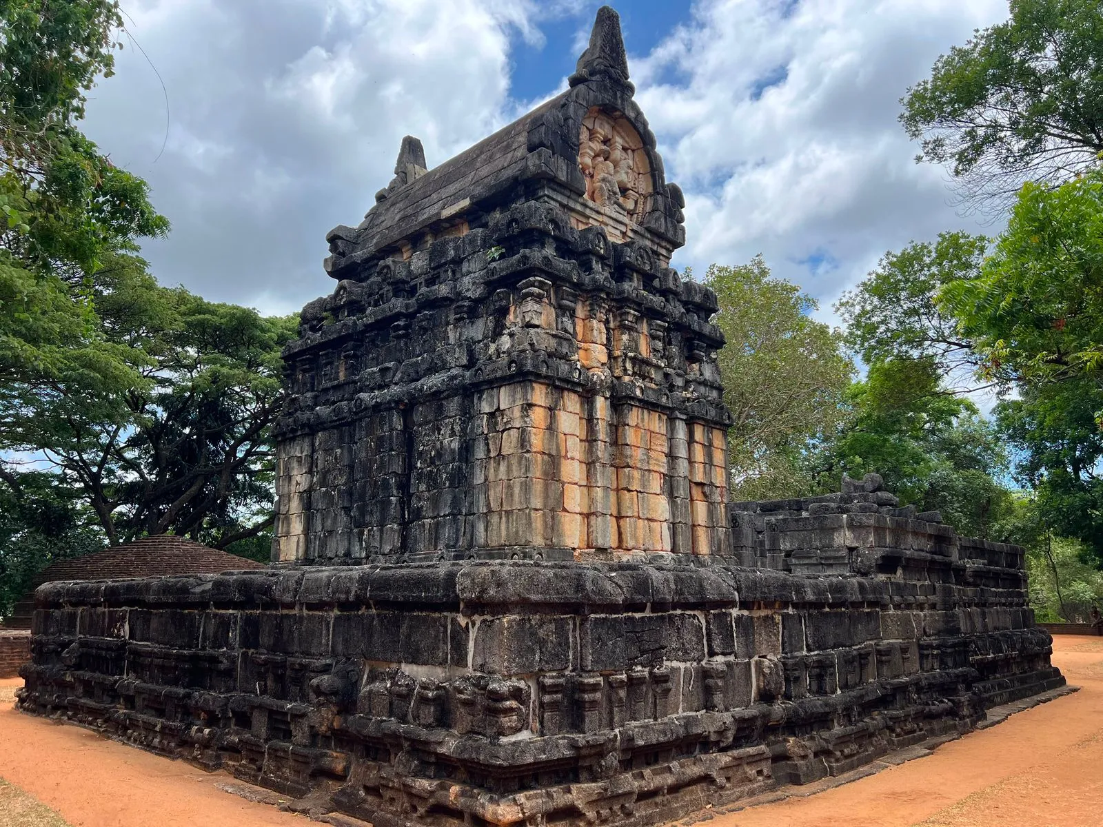 A carved stone temple standing among trees on the road to Kandy