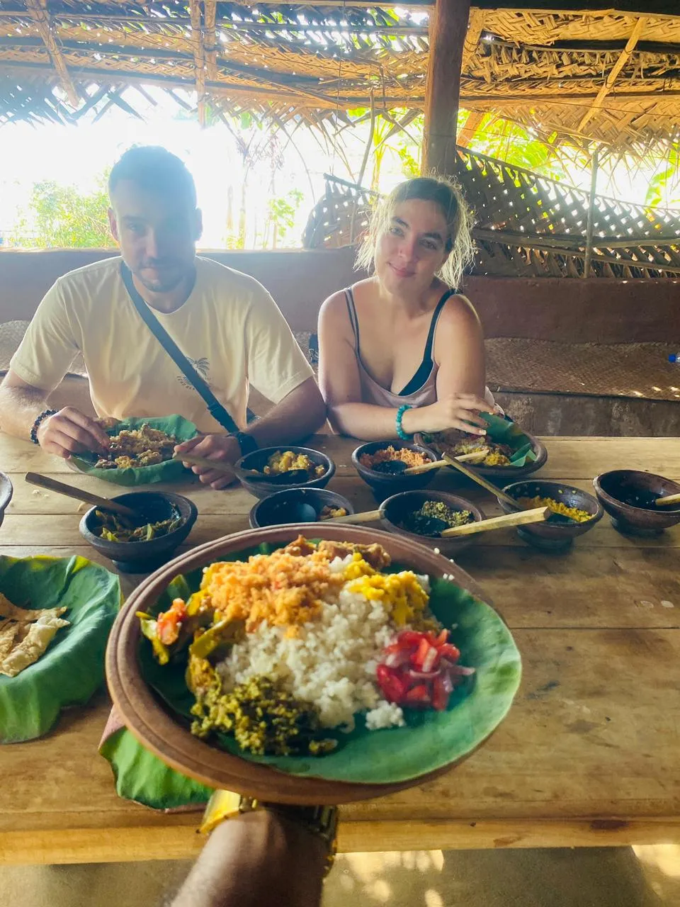 Rice and curry served on banana leaf in clay bowls at a village table